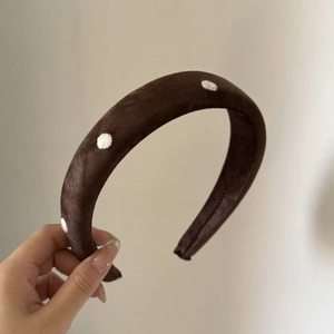 Detail of a dark brown velvet headband with white polka dots and thick sponge padding