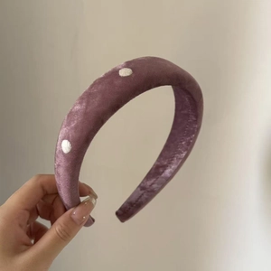 Close-up of padded mauve velvet headband with elegant white embroidered polka dots