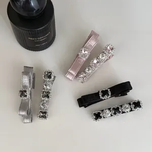Vue détaillée de pinces à cheveux avec nœuds en satin et strass en rose, gris et noir