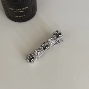 Détail d'une pince à cheveux argentée avec cristaux gris rectangulaires et strass brillants