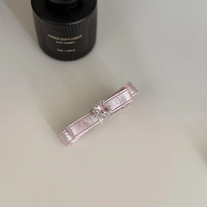 Vue détaillée d'une barrette en satin rose ornée d'un cristal carré rose et petits strass