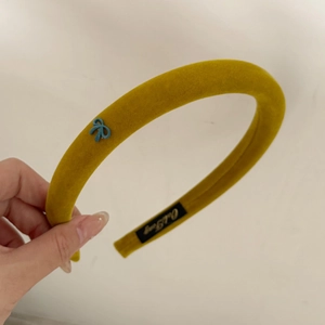 Detail of yellow velvet headband with blue bow showing thick texture and contrast colors