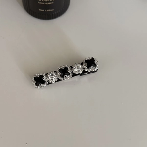Détail de la pince à cheveux en satin avec pierres carrées noires et strass clairs
