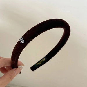 Detail of dark brown velvet headband featuring an elegant silver metal bow buckle