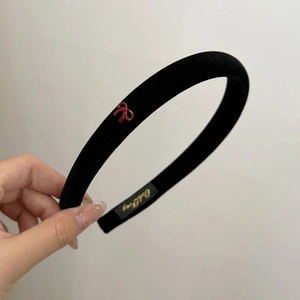 Close-up of black velvet headband featuring a small burgundy bow in vintage style