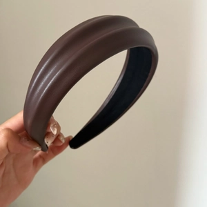 Gros plan détaillé du serre-tête rembourré en cuir PU marron foncé à design plissé