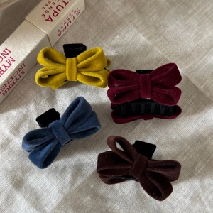Vintage velvet bow hair clips in yellow, red, blue and brown on a beige linen background