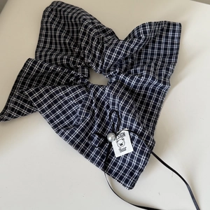 Elastico per capelli a scacchi con fiocco nero e perla su sfondo bianco