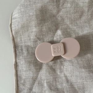Pink acetate flower bow hair clip with engraved lettering on a linen background