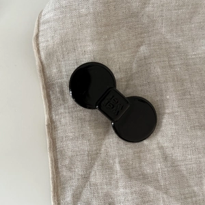 Macro shot of black acetate bow hair clip with Wer Wer engraving on linen background