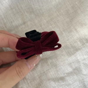 Detail view of a vintage burgundy velvet bow hair clip with black claw for styling