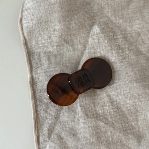 Detailed macro view of an amber tortoiseshell acetate bow hair clip with Wei engraving