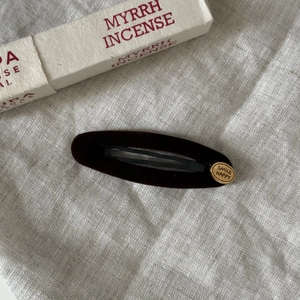 Retro velvet oval hair clip with gold Smile Happy label on textured linen background