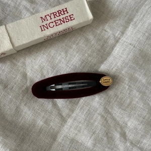 Close-up of vintage dark red velvet oval hair clip with gold Smile Happy metal detail