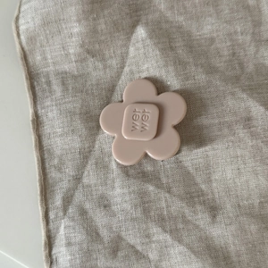 Detailed close-up of a nude pink acetate floral hair clip with embossed letter design