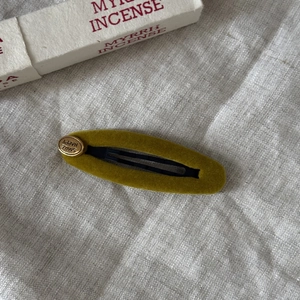 Detailed close-up of dark green velvet hair clip with golden Happy Smile engraving