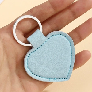 Detail shot of heart-shaped light blue leather keychain showing lychee texture and stitching