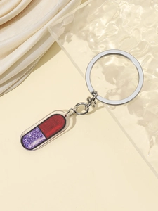 Vista dettagliata del portachiavi a pillola in acrilico con glitter rossi e viola scintillanti