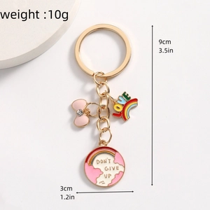Nahaufnahme eines goldenen Schlüsselanhängers mit Regenbogen-Charm und Mutmacher-Slogan