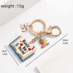 Detail view of rainbow heart balloon charm and book pendant on a gold keychain