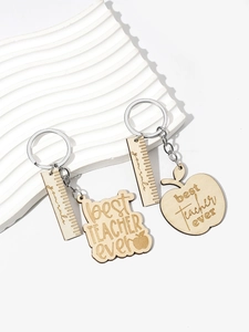 Detail of wooden Teacher appreciation keychains with apple and ruler charms on a white tray