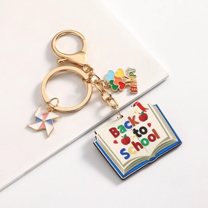 Detail of Back to School keychain featuring book, apple, and colorful windmill charms