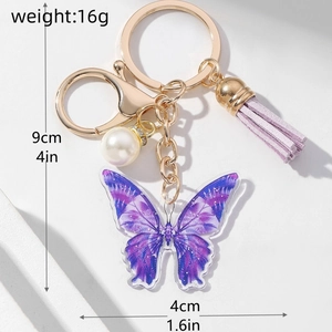 Detail showing 9cm purple butterfly keychain with pearl tassel and golden metal hardware