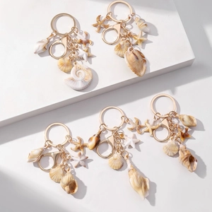Detailed view of ocean life shell and starfish charms on gold keychains on white pedestals