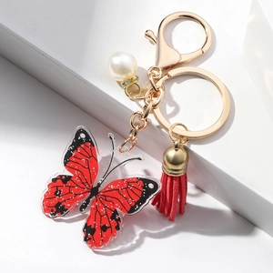 Colorful acrylic butterfly keychain with red tassel and pearl on a white background