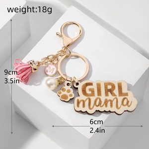 Detail of wooden GIRL mama keychain with pink tassel, pearl, and gold metal clasp