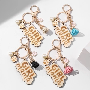 Detail view of the wooden GIRL MAMA keychains with colorful tassels and pearl charms