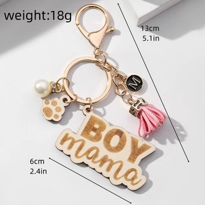 Detail of wooden BOY mama keychain with floral accents, pearls, and a pink tassel