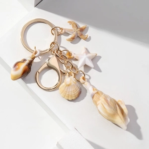 Detail of ocean-themed keychain featuring starfish, shells and golden lobster clasp