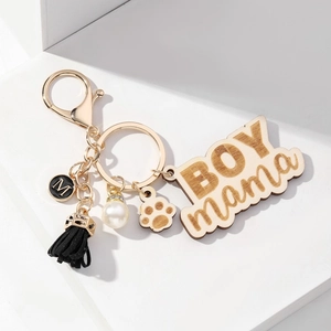 Detailed view of BOY MAMA wooden keychain with suede tassel and white pearl pendant
