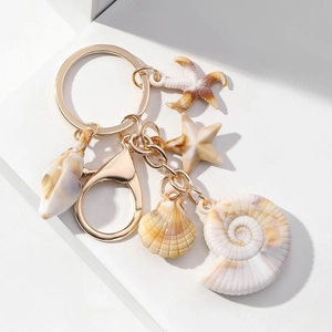 Detailed close-up of ocean-themed seashell and starfish pendants on a golden keychain
