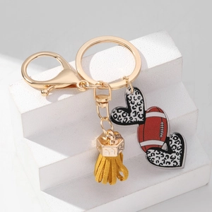 Detail of leopard print heart and rugby ball keychain with ginger leather tassel