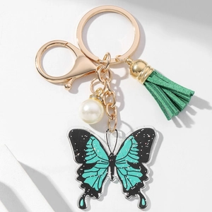 Detail of light green acrylic butterfly keychain with white pearl and green suede tassel