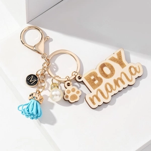 Floral BOY MAMA wooden keychain with paw print, blue tassel and white pearl on white pedestal