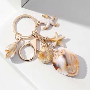 Detail view of seaside shell keychain with gold metal ring and acrylic starfish charms
