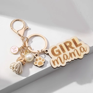 Detailed view of GIRL MAMA wooden keychain with white tassel, pearl, and M letter charm