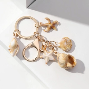 Detailed macro view of ocean-themed resin starfish and seashell charms on golden keychain
