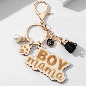 Macro detail of BOY MAMA wooden keychain with black tassel, paw charm and pearl