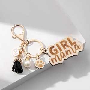 Detail of wooden GIRL MAMA keychain with black tassel, white pearl and gold hardware