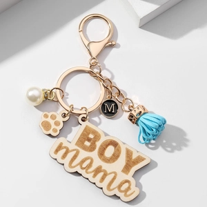 BOY MAMA keychain with blue tassel, pearl, paw pendant and letter M charm on white background