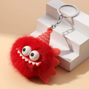 Red plush monster keychain with big eyes and sharp teeth on white display steps