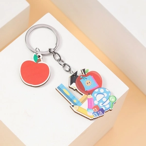 Close-up of red apple and school supply acrylic pendants on teachers day keychain