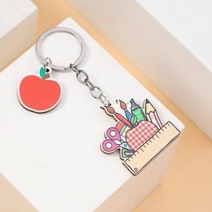 Apple teacher keychain with school supplies pattern charms on a white display stand