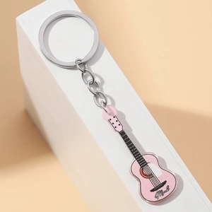 Pink acrylic guitar keychain with Music script leaning on a white minimalist display stand