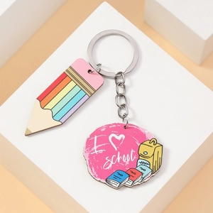 Macro detail of wooden rainbow pencil charm and pink school theme pendant on a key ring