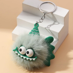 Detail of green furry monster keychain with striped hat and big eyes on white stand